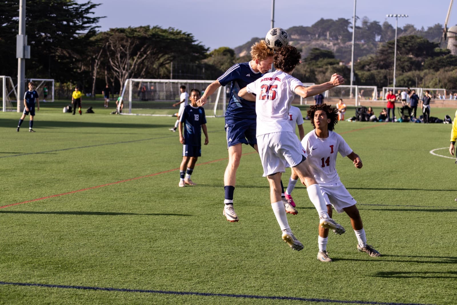 Two high school soccer players contesting an aerial ball during a match.